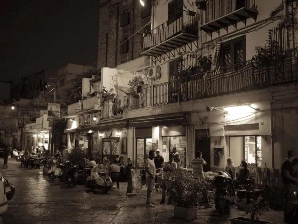 pair Balconies and bar tables on a Palermo backstreet at night