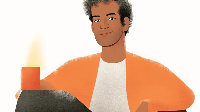 Smiling man in orange cardigan, next to a glowing orange candle.
